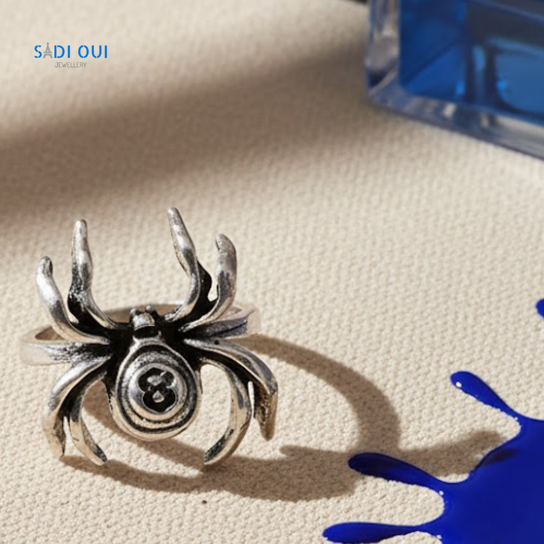Anel Aranha Base em aço inoxidável prateado em fundo bege com detalhe de líquido azul