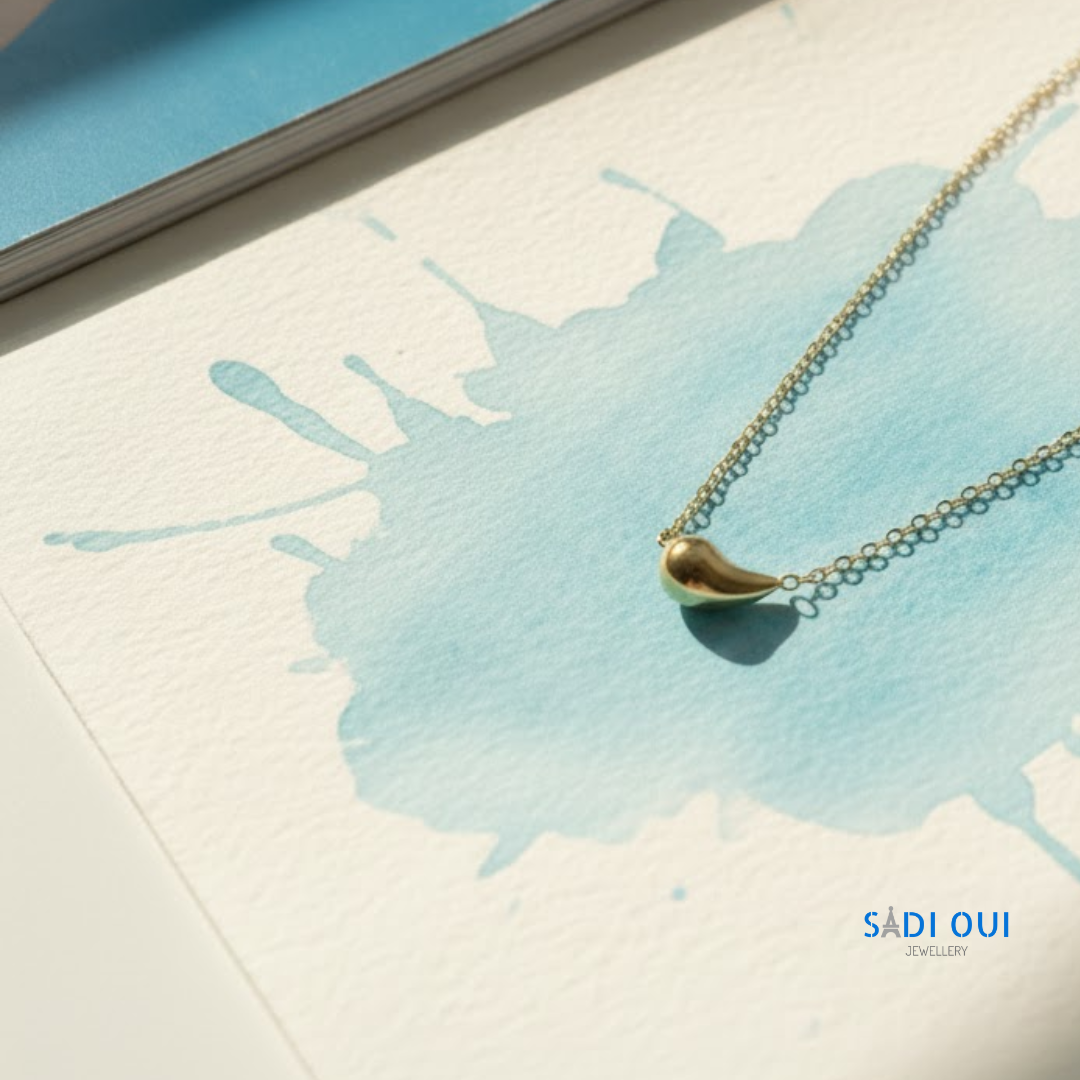 Pulseira Pop Drop em aço inoxidável dourado em fundo claro com mancha azul
