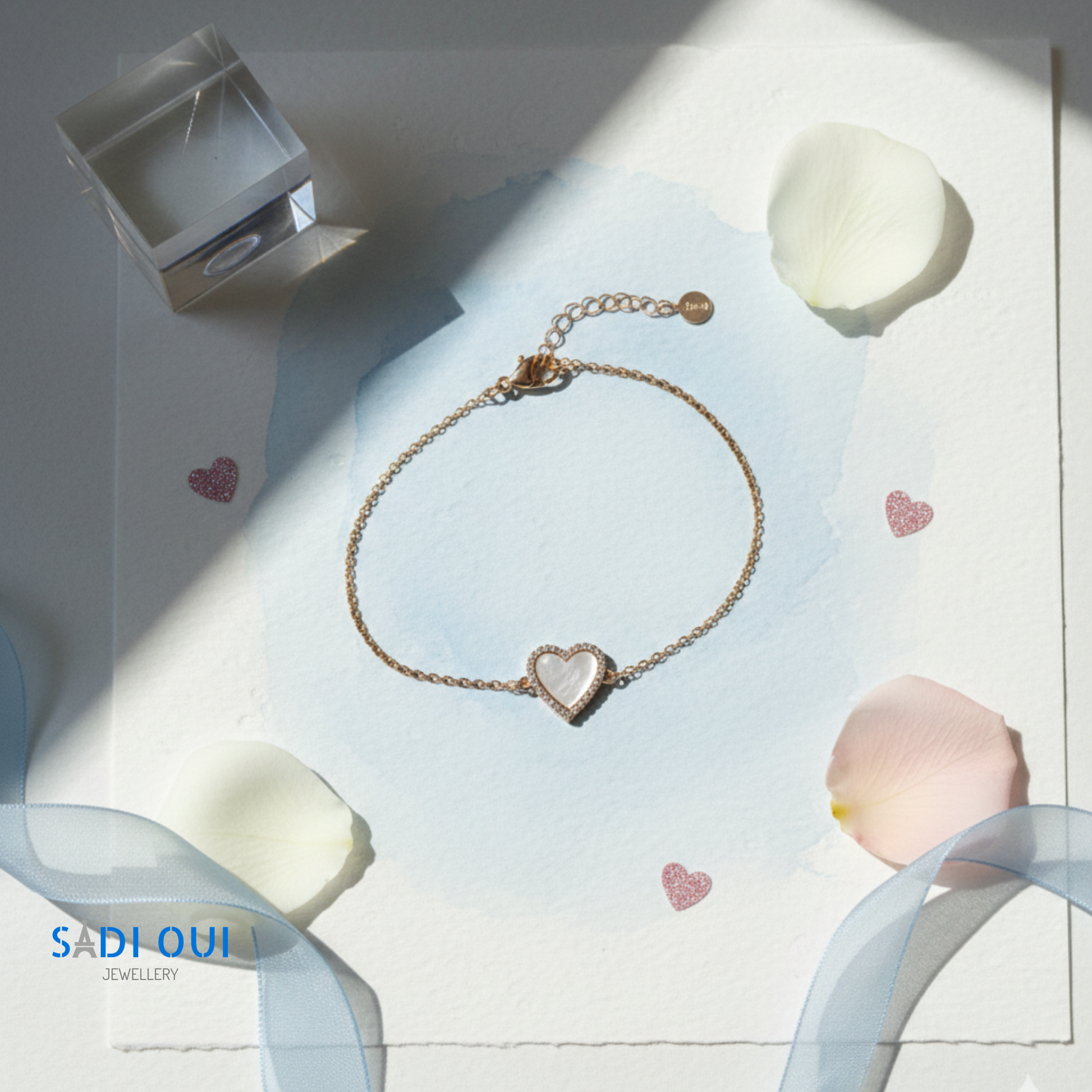 Pulseira Sentir SADI OUI em aço inoxidável dourado com coração branco em fundo claro em cenario