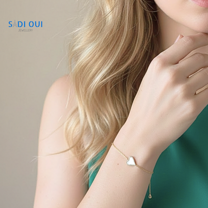 Pulseira Sentir SADI OUI em aço inoxidável dourado com coração branco em fundo claro em modelo